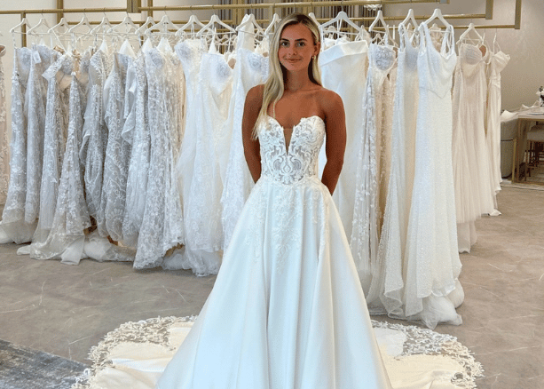 Bride trying on a lace wedding dress inside a bridal boutique showroom