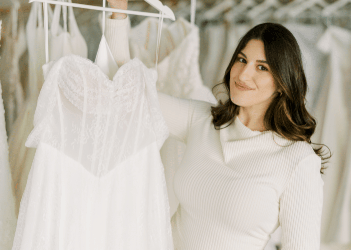Bride holding a lace wedding dress while shopping for her bridal gown in a boutique.