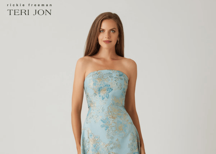 Woman wearing a light blue strapless fitted dress with gold floral detailing