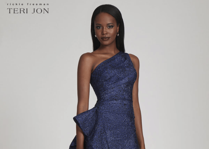 Black woman wearing a navy blue one-shoulder textured cocktail dress with a draped peplum detail